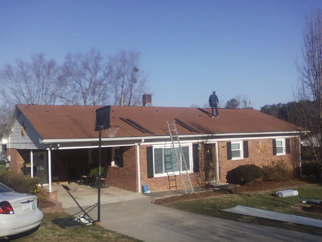 Roofer stripping a shingle roof on a brick ranch before metal panels in Linden