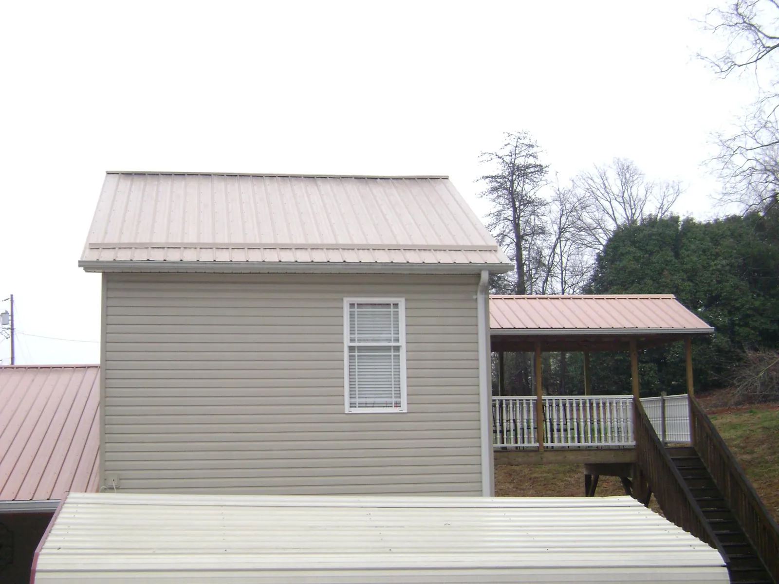Tan metal roofs on a two story addition and attached porch, from a Roof Replacement job in Linden